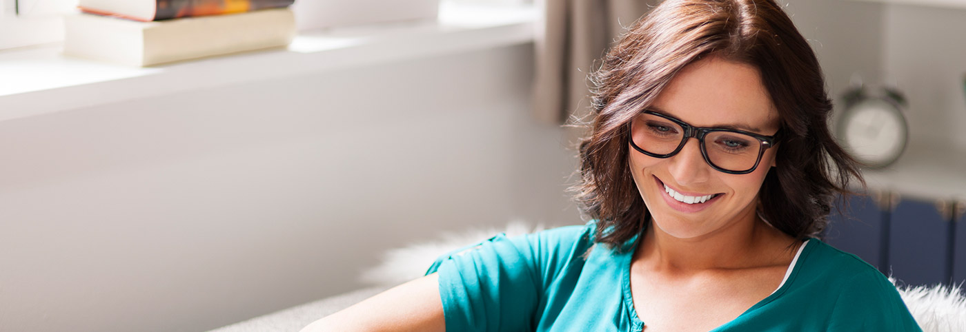 lady sporting glasses in teal blouse grinning