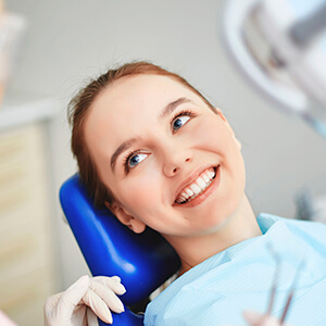 Female patient in dental chair smiling at dentist