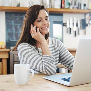 Smiling woman on phone looking at laptop