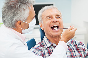 Older male patient being examined by dentist