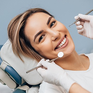 Smiling woman in dentist’s chair receiving treatment