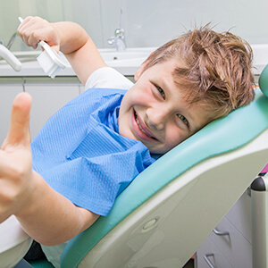 Young boy giving thumbs up in dental chair