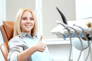 Dental patient giving thumbs up for SureSmile clear aligners