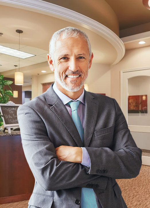 Dapper elderly man in suit smiling in dental office with arms crossed