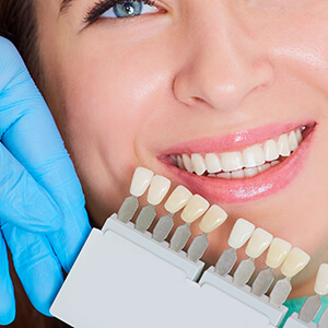 Patient comparing teeth with teeth color chart