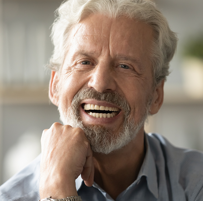 Senior man in a collared shirt smiling with dentures in Sparks