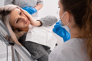 a woman holding her mouth in pain at the dentist’s office