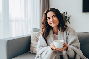 Smiling woman resting at home with cup of tea