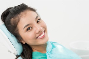 Woman in green shirt smiling in dental chair