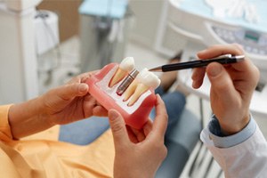 Dentist showing patient model of dental implant in Sparks, NV