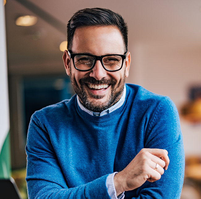 Man in a blue sweater smiling with dental inlays and onlays