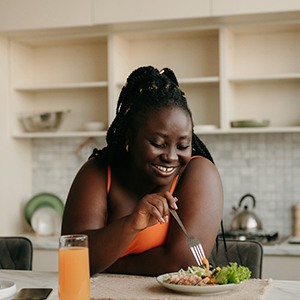 Woman smiling while eating healthy meal at home