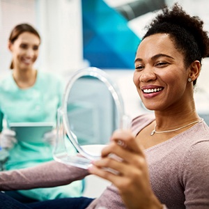 Woman smiling at reflection in handheld mirror