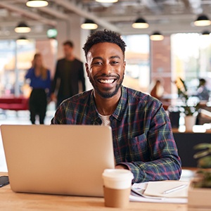 Man smiling while working on laptop