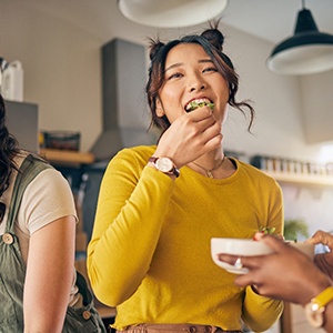 Woman smiling while eating lunch with friends at home