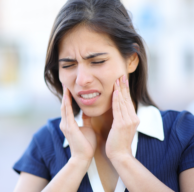 Woman holding both sides of her jaw in pain before TMJ treatment in Sparks